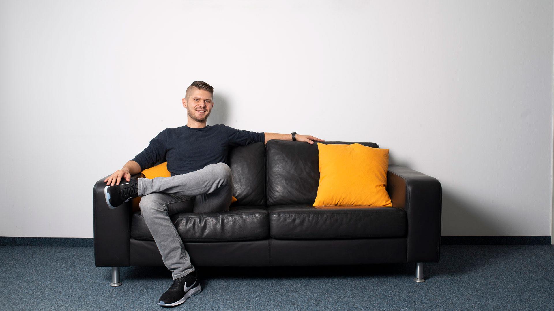 Ein Mitarbeiter von nova sitzt entspannt auf einer Couch und freut sich auf Bewerbungen